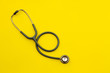 © Tony - Above shot of a stethoscope puts on the left side of a table on a yellow background.