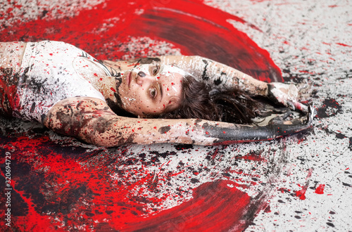Fotomural Young sexy woman in underwear, sportswear, artistically abstract painted with black, red, white, paint, lies on the floor and spreads the paint on the floor in the form of angel wings