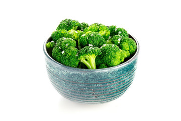 A bowl of cooked broccoli with salt on a white background