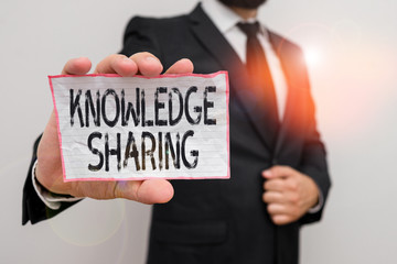 Poster - Word writing text Knowledge Sharing. Business photo showcasing deliberate exchange of information that helps with agility Male human wear formal work suit office look hold notepaper sheet use hand