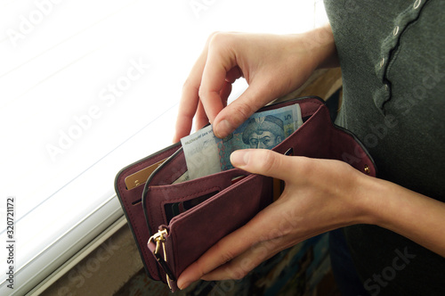 Fotomural Women's hands choose the Ukrainian hryvnia in cash wallet.