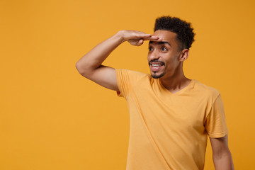 smiling young african american guy in casual t-shirt posing isolated on yellow orange wall backgroun