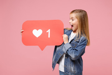 Surprised little kid girl 12-13 years old in denim jacket isolated on pastel pink background in studio. Childhood lifestyle concept. Mock up copy space. Hold huge like sign from Instagram heart form.