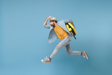 Side View Of Excited Traveler Tourist Man In Yellow Clothes Isolated On Blue Background. Male Passenger Traveling Abroad On Weekends. Air Flight Journey Concept. Jumping Like Running, Hold Suitcase.