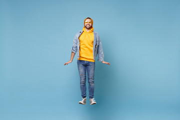 Wall Mural - Smiling young hipster guy in fashion jeans denim clothes posing isolated on pastel blue background studio portrait. People sincere emotions lifestyle concept. Mock up copy space. Jumping, having fun.