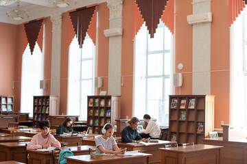 Poster - Two rows of desks in college library and students working individually while preparing for seminar after classes