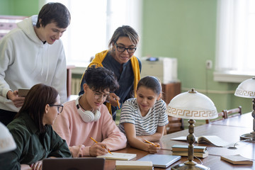 Aufkleber - Two students pointing at notes of teenage guy in his notepad while choosing name for project in group in college library