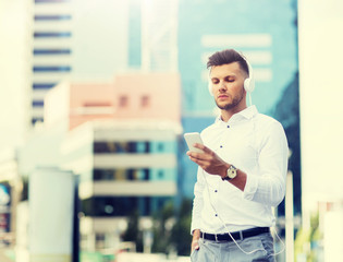 Wall Mural - people, technology and lifestyle - happy young man with headphones and smartphone listening to music in city