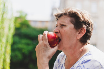 Close-up shot of senior woman eating apple outside