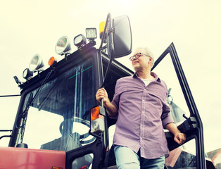 Canvas Print - farming, agriculture and people concept - senior man or farmer getting out of tractor at farm