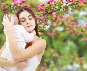 Wall Mural - family and motherhood concept - happy smiling young mother with little baby over natural spring cherry blossom background