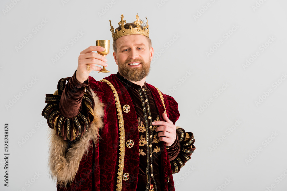 smiling king with crown holding cup isolated on grey - obrazy, fototapety, plakaty 