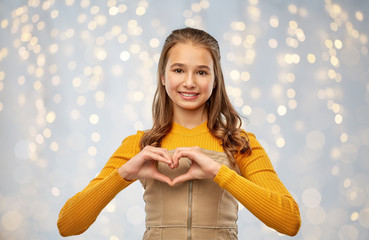 Sticker - love, people and valentine's day concept - smiling teenage girl making hand heart gesture over festive lights background