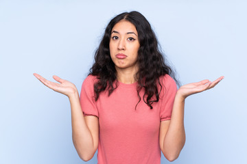 Wall Mural - Mixed race woman wearing a sweater over isolated blue background having doubts with confuse face expression