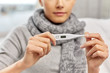 people, health and fever concept - close up of sick woman in scarf measuring temperature by thermometer at home