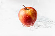 Jabłko w deszczu, polewane wodą. Widzoczne krople