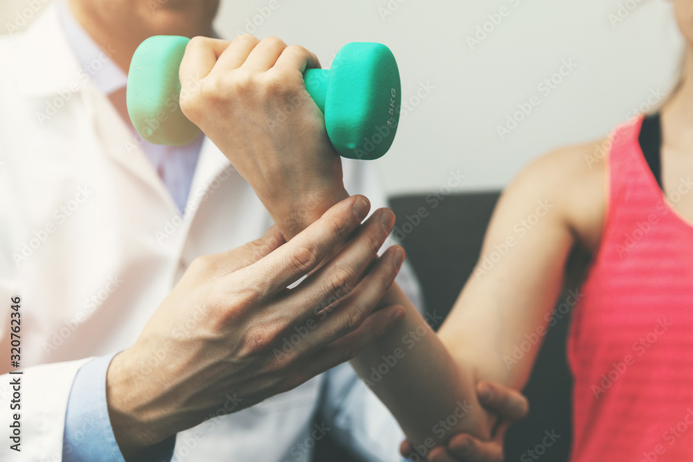 physiotherapy - physiotherapist help woman patient to recover from hand injury at home. dumbbell exercises