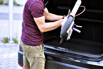 Man pulls electric scooter out of car.