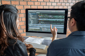 Leinwandbilder - Two professional programmer cooperating and working on web site project in a software developing on desktop computer at company, codes and typing data code, Programming with HTML, PHP and javascript