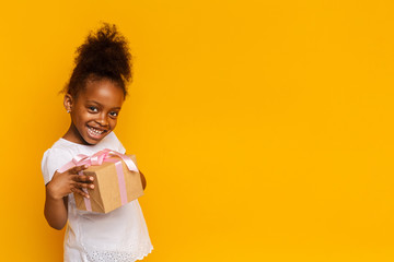 Cute little girl smiling and holding gift box