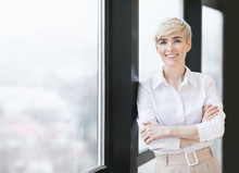 Smiling Mature Lady Crossing Hands Standing Near Window In Office