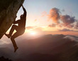 Rock climbing. Young male risky climber trying staying on challenging cliff route. Scenic mountain landscape with sunrise sky on background. Fail, difficulties, overcoming obstacles. Copy space
