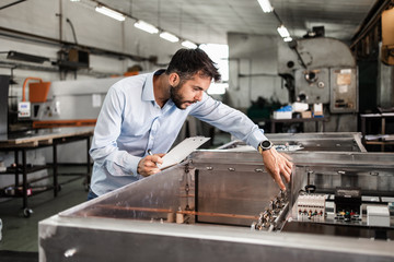 Middle age businessman doing quality control checking at industry production. Factory for industrial production of electric housings and surge arresters.