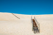 © EZ PHOTOS - Wooden stairs over sand dune with blue sky