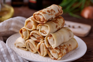 Russian pancakes with filling, lying on a plate with a slide