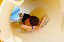Little Happy Kid Boy Sliding On Water Slide Tube In Resort Park. Healthy Child Having Fun.