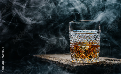 Fotomural glass of whiskey with ice on a wooden table surrounded by smoke