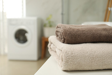 Sticker - Stack of clean towels on table in laundry room. Space for text