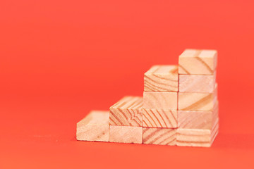 wood block stacking as step stair on wooden table. Business concept for growth success process. Copy space. on red background