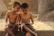Two Asian boys are interested in learning different things on their tablets. The concept of distance education via the internet.