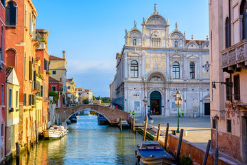 Narrow canal with bridge and facade of hospital Giovanni and Paolo in Venice, Italy. Architecture and landmark of Venice. Cozy cityscape of Venice.