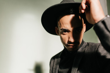 Refined man in elegant black hat looking to camera. Close-up studio portrait of serious african male model.