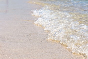 Transparent sea waves with white foam and clean yellow sand. Summer background.  Sea coast with a beautiful soft wave. blue sea wave with white foam on a clean sandy shore, selective focus. 