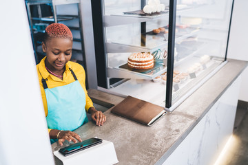 Wall Mural - Optimistic black worker browsing tablet in cafeteria