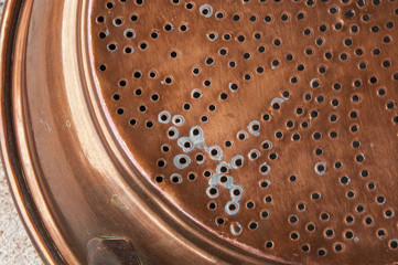 Antique copper sieve on concrete background.