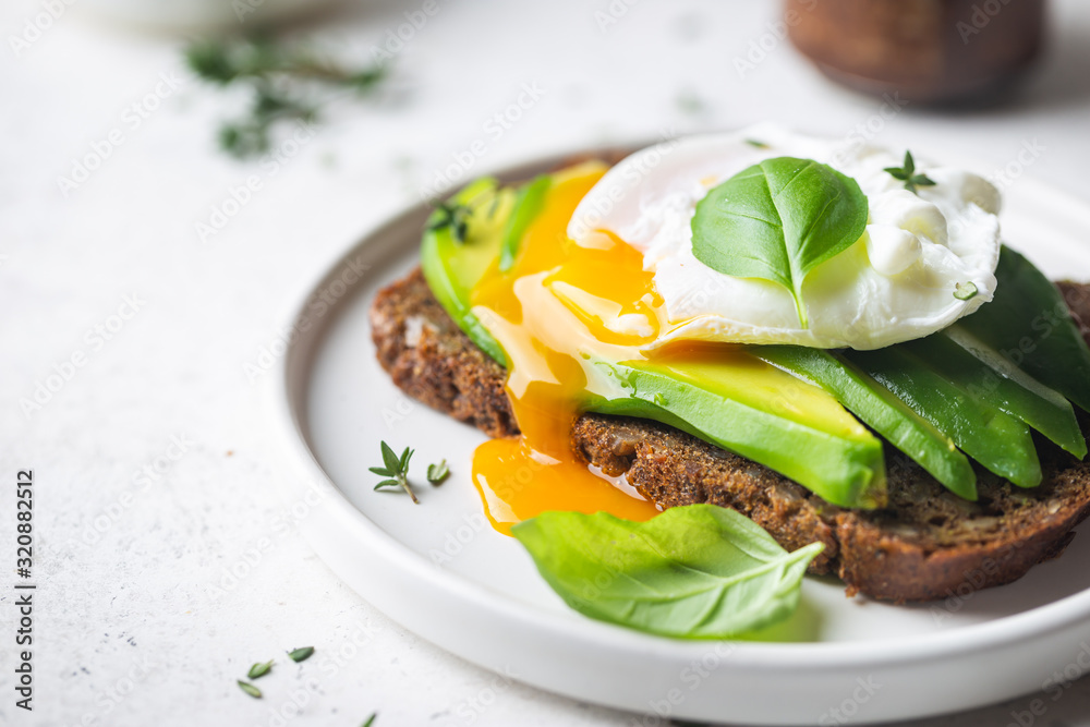 Healthy breakfast whole wheat toasted bread with avocado and poached egg over white background - obrazy, fototapety, plakaty 