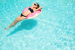 © Iurii - Enjoying suntan woman in black bikini on the inflatable mattress in the swimming pool. Summer vacation concept