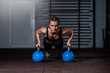 © Srdjan - Young strong fit sweaty muscular girl with big muscles doing push ups on two big old heavy kettlebells with her hands for hard core cross workout training on the gym floor real people
