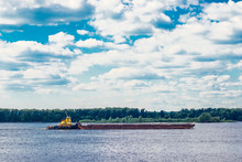 Yellow Tugboat Pulling Barge Along The River