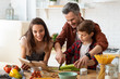 © deniskomarov - Mother, father, son chopping vegetables on kitchen