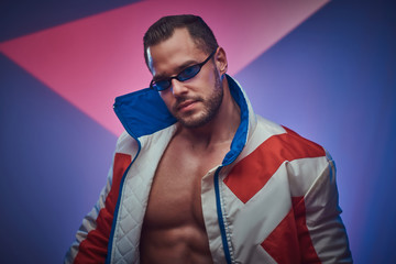 Wall Mural - Young attractive man in sunglasses is posing for photographer on the neon background.