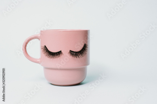 The concept of a girl s leisure, a pink mug of coffee of a dream, tender blue color with closed eyes. Fluffy eyelashes on a pastel background, copy space