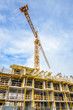 © karamysh - High-rise building under construction. The site with cranes against blue sky