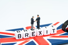 Man Checking Hand On Cube Block With Alphabets Building The Word BREXIT On Union Jack UK Flag With White Copy Space Background Using As United Kingdom Leaving EU European Union Concept