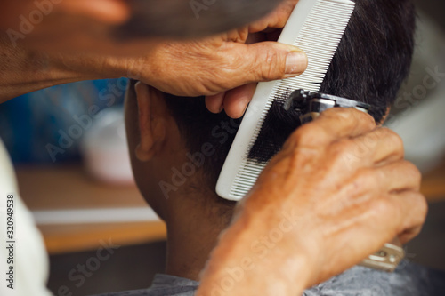 Fotografía Closeup hand of hairdresser cutting hair with clipper at local barber shop