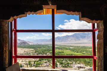 Amazing scenic view through the window of Thiksay Monastery or Thiksay Gompa to the green valley village of the Indus river, Leh Ladakh, Jammu and Kashmir, India.